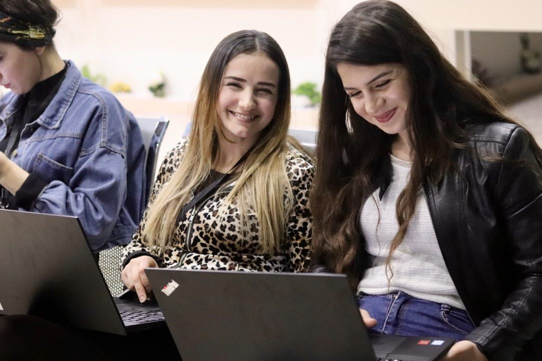 Two learners laughing at their laptops