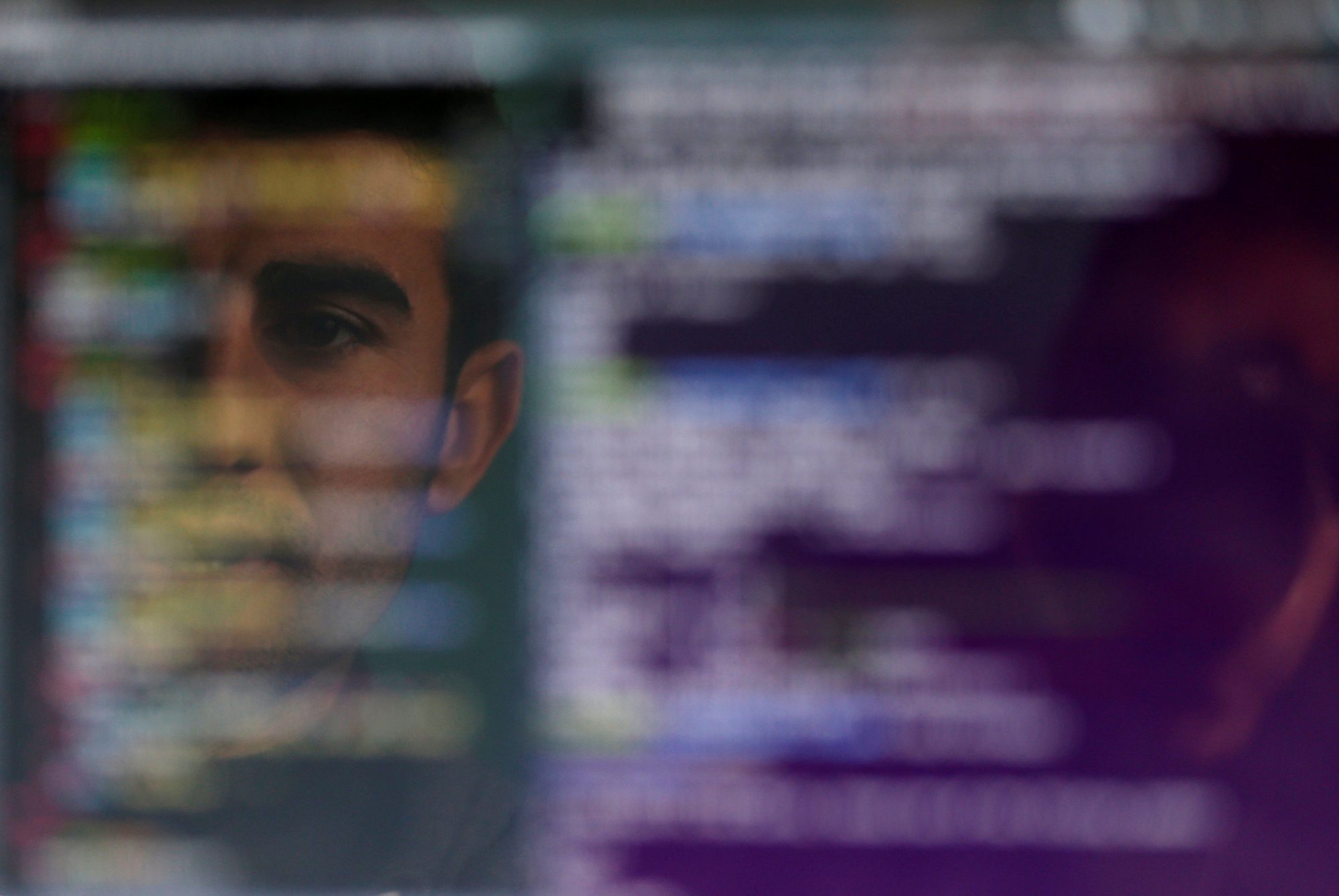 A developer’s face reflected in a screen of code