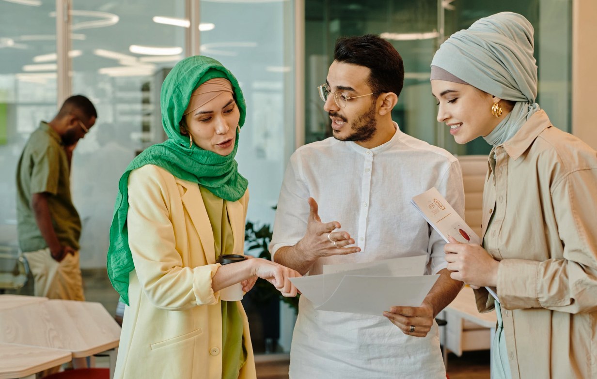Three young professionals talking over documents in an office