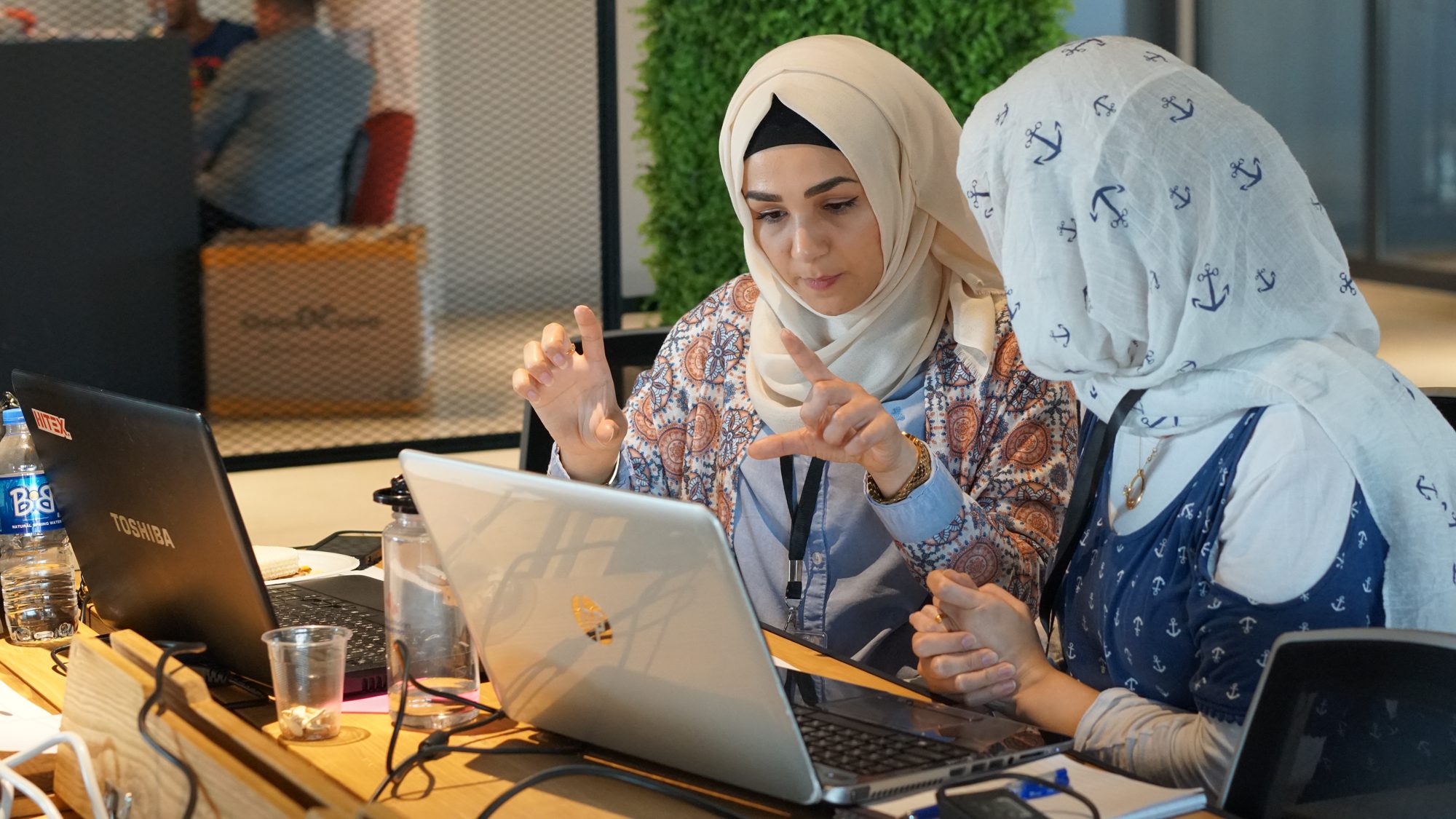 Two learners working through a problem at a laptop